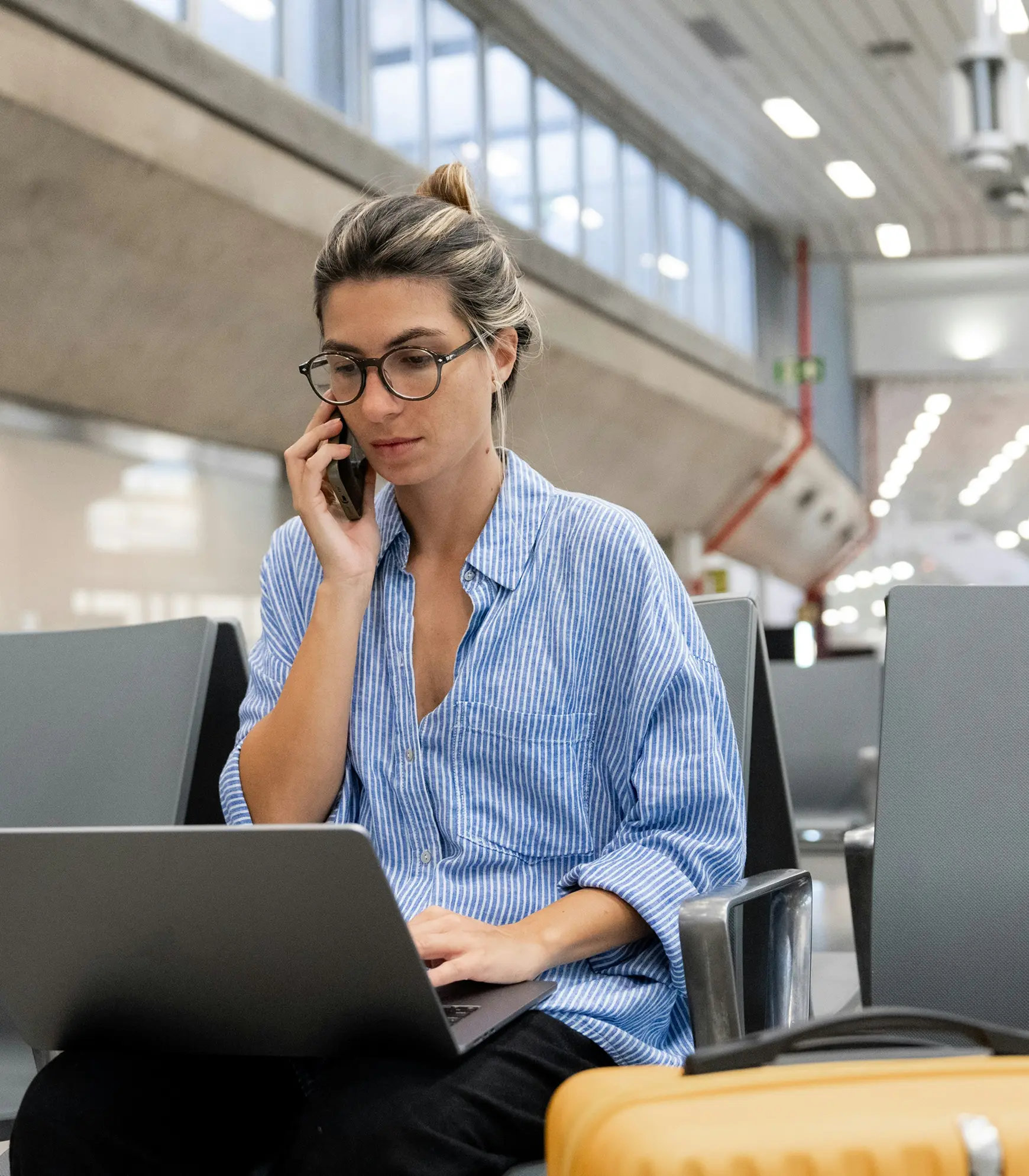 Traveler on the phone with HelloGov support while working on a laptop at the airport